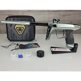 USED DLX Luxe X Silver Black Paintball marker with case and accessories on a white surface.