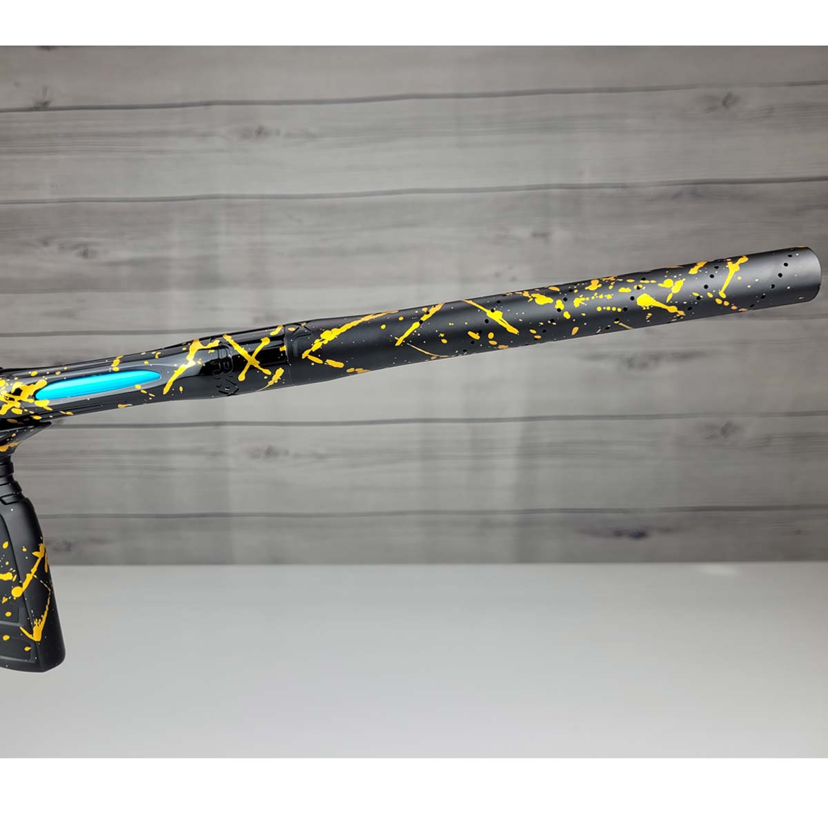 Right side barrel close up USED HK Army Shocker AMP Prestige Black Gold Splash on a woodgrain background