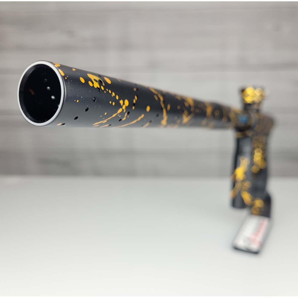Barrel tip close up USED HK Army Shocker AMP Prestige Black Gold Splash on a woodgrain background