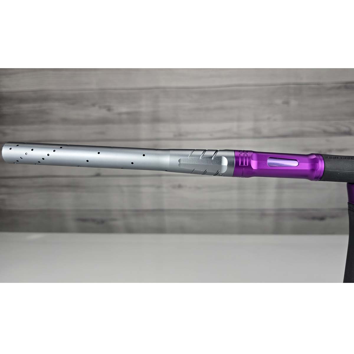 Close up of left side barrel Purple and silver USED Planet Eclipse LV2 Paintball Marker Havoc Grey Purple on a white surface with a wooden background