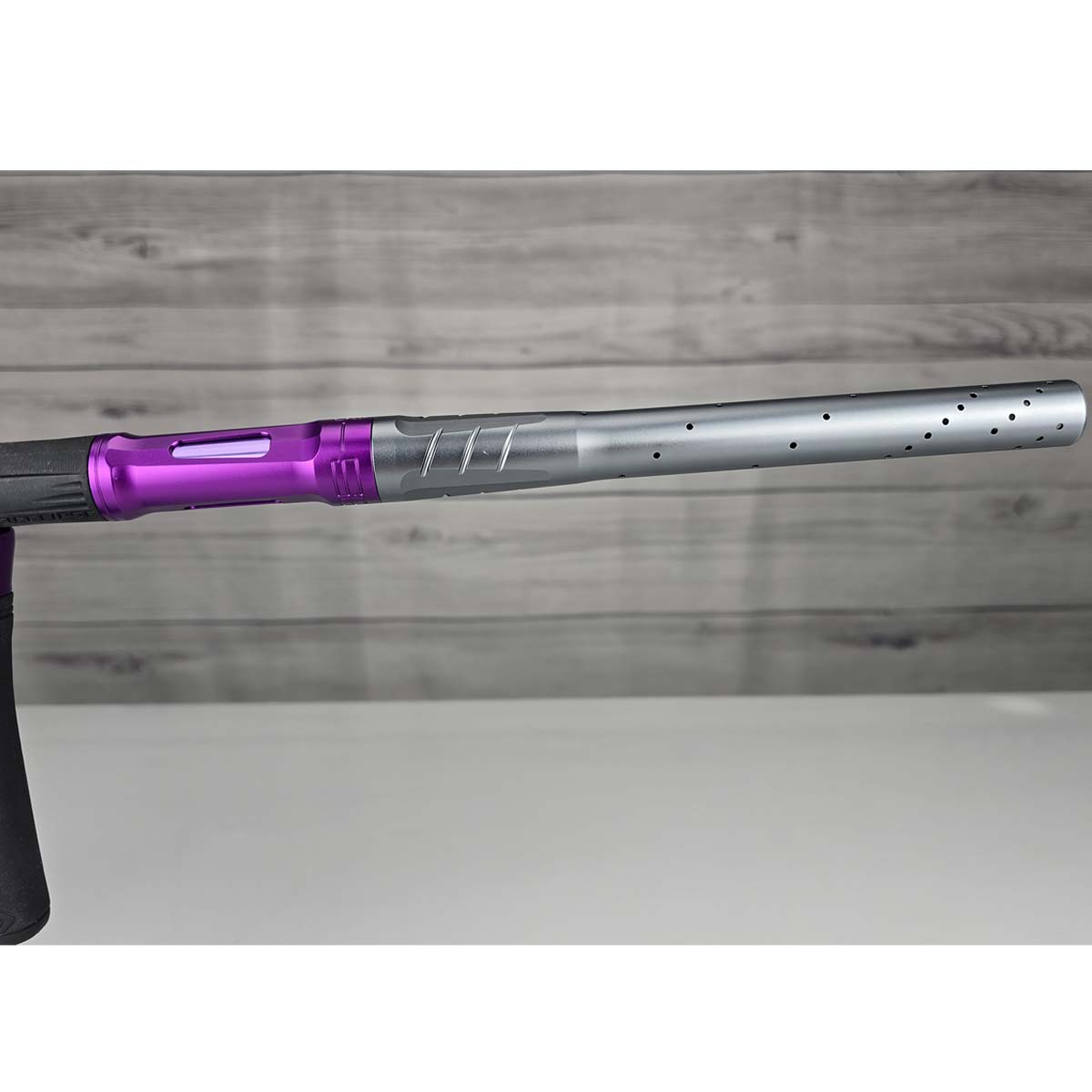 Close up of right side barrel Purple and silver USED Planet Eclipse LV2 Paintball Marker Havoc Grey Purple on a white surface with a wooden background