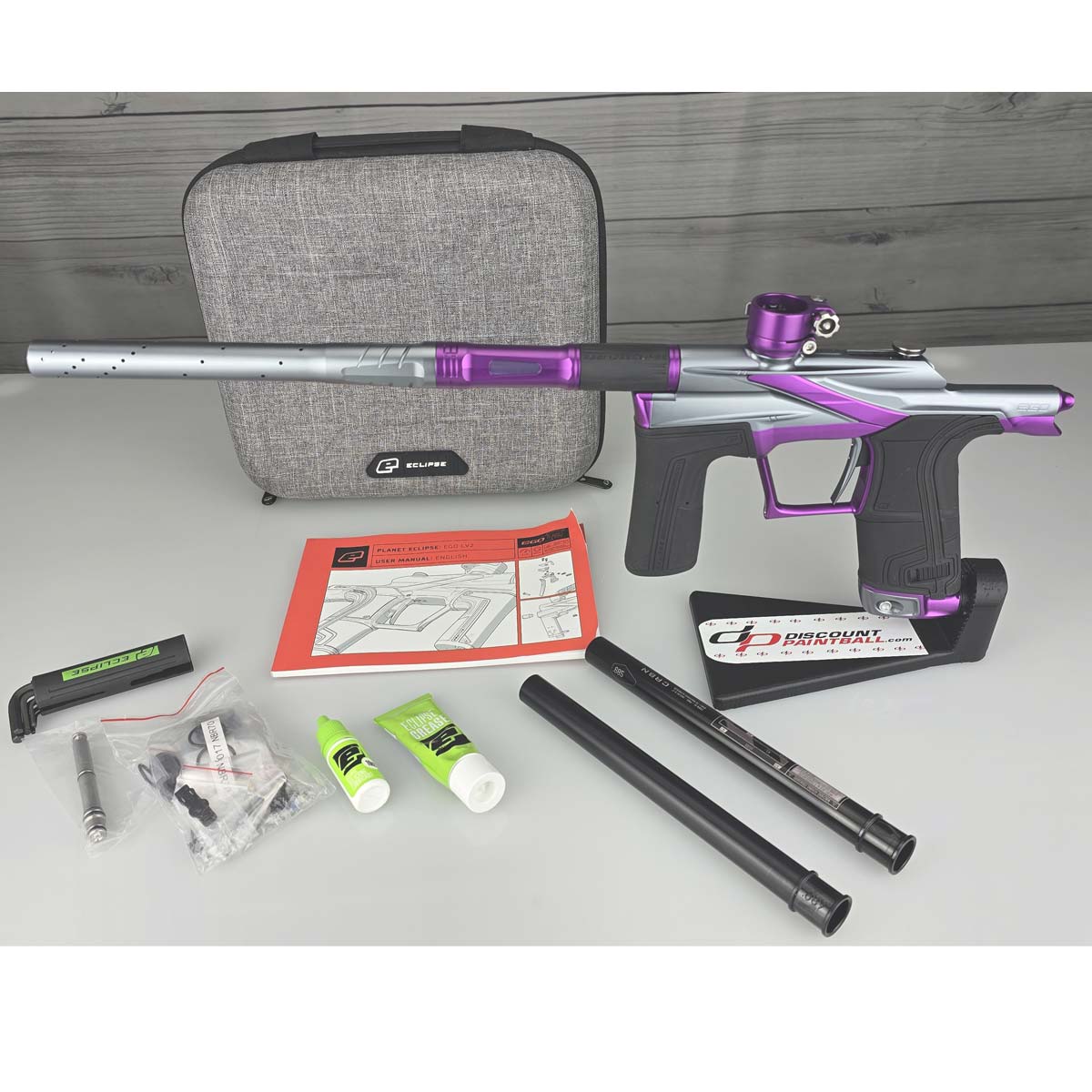 Purple and silver USED Planet Eclipse LV2 Paintball Marker Havoc Grey Purple with case and accessories on a white surface with a wooden background