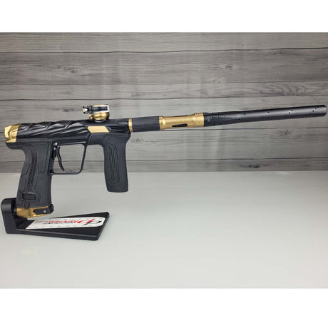Black and gold USED Planet Eclipse Infamous CS3 paintball marker on a white surface with a wooden background