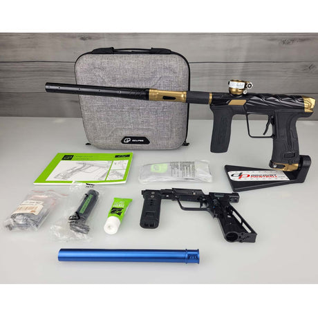 USED Planet Eclipse Infamous CS3 paintball marker and accessories on a white surface with a gray case in the background.
