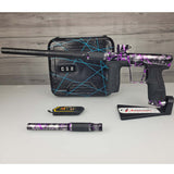 Left side USED Planet Eclipse CS2 Paintball Marker Black Purple Grey Splash with case and barrel sock and second barrel back on a woodgrain background