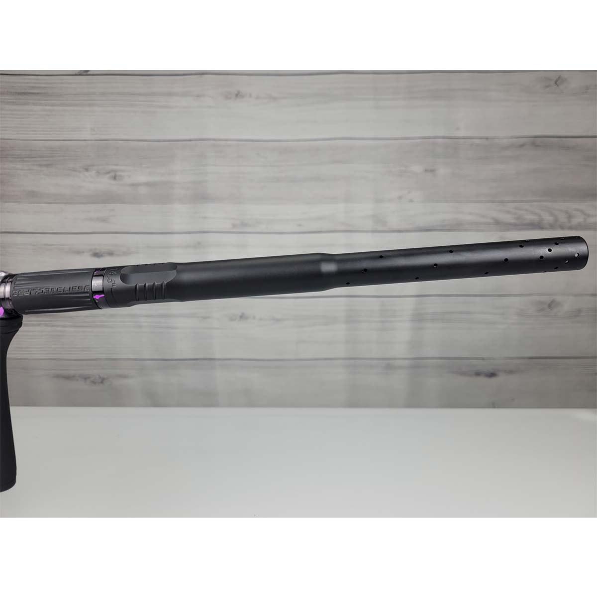 Right side barrel USED Planet Eclipse CS2 Paintball Marker Black Purple Grey Splash on a woodgrain background