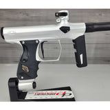 Right side body USED Shocker Era Silver black paintball marker in a stand on a woodgrain background.