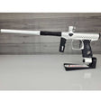 Left side USED Shocker Era Silver black paintball marker in a stand on a woodgrain background.