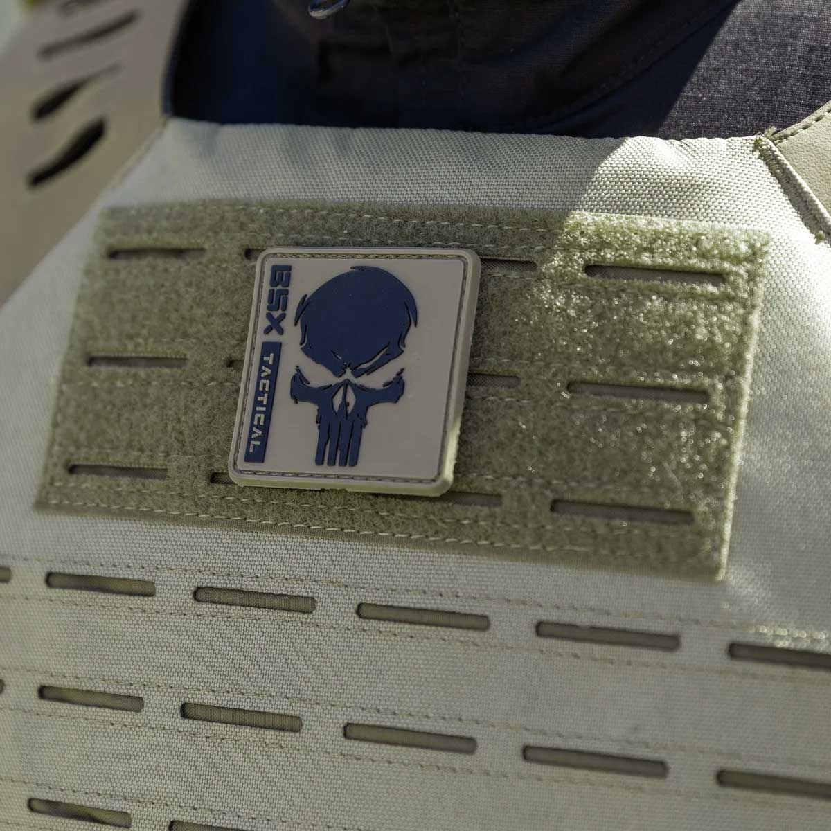 Close up patch detail olive green HK Army BSX Skull Plate Carrier for molle attachments for airsoft and paintball, shown on a person in tactical attire