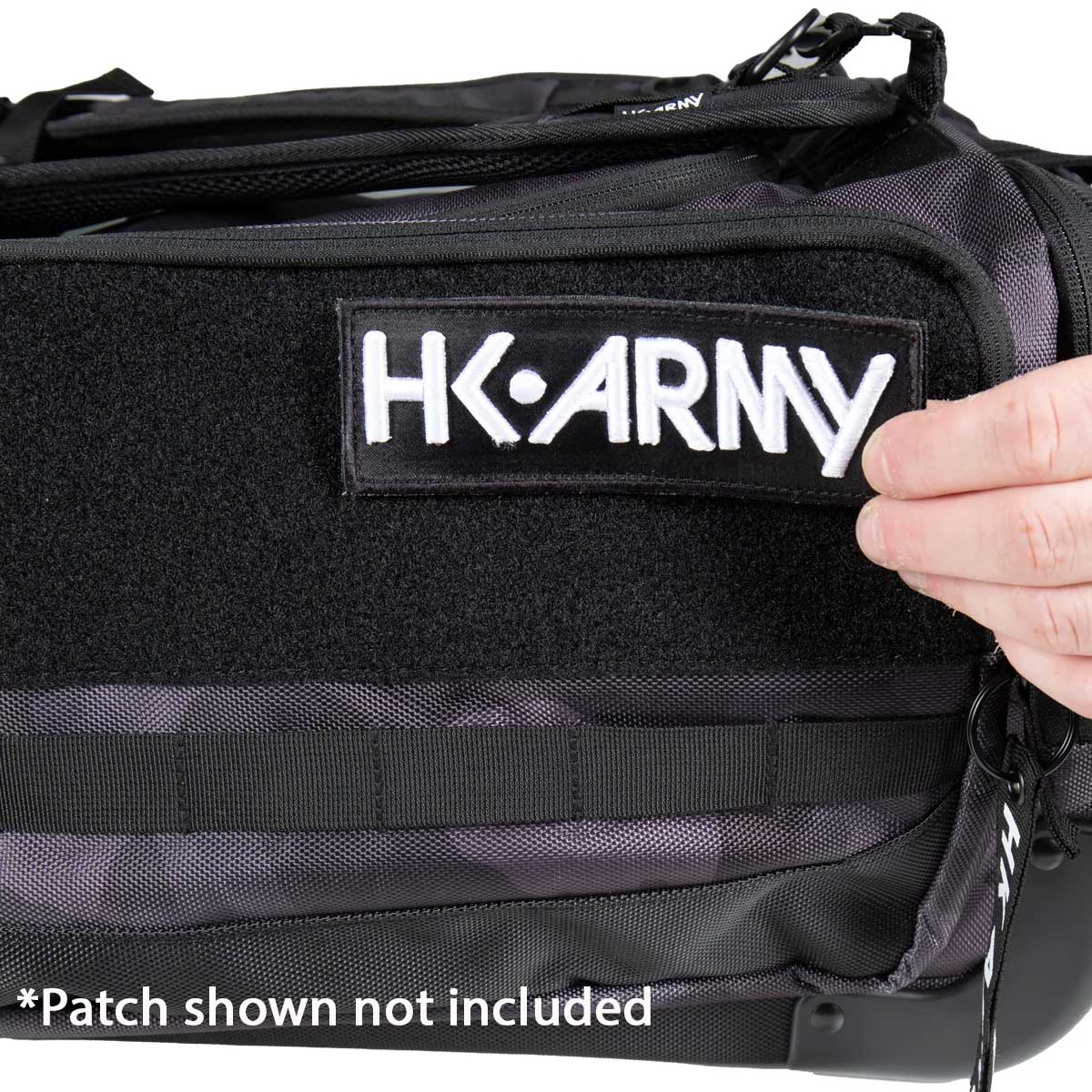 Close-up of a black tactical-style bag with a Velcro patch area and the embroidered text 'HK ARMY' on the front. A hand is touching the patch, and a note at the bottom says '*Patch shown not included'.