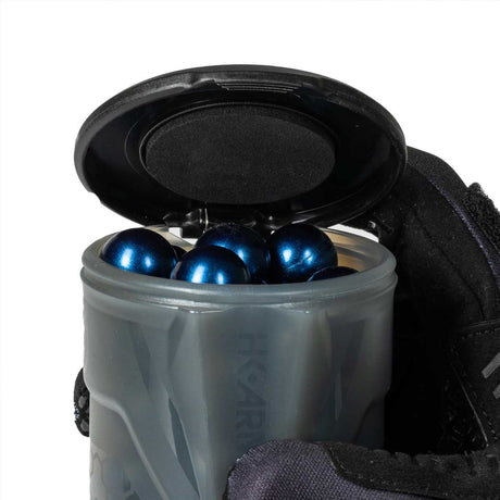 One open HK Army Apex 150 Round Paintball Pod in Light Smoke color containing blue paintballs being held by a gloved hand on a white background
