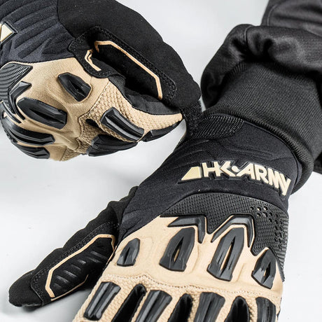 Close of person wearing A pair of black and tan paintball or airsoft HK Army Hardline Armored Full Finger Gloves Tactical gloves shown against a plain white background.