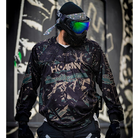 Black green and tan HK Army HSTL Jersey Jungle Camo long sleeve on a person on a busy background