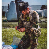 Person dressed in camo with a paintball mask loading a Left  Black and silver T4E Walther PPQ .43 Cal 8rd CO2 Paintball Magazine on a grassy background