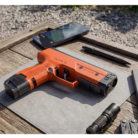 Byrna CL-XL orange left side view with 7 round magazine and 12 gram co2 on a wood table