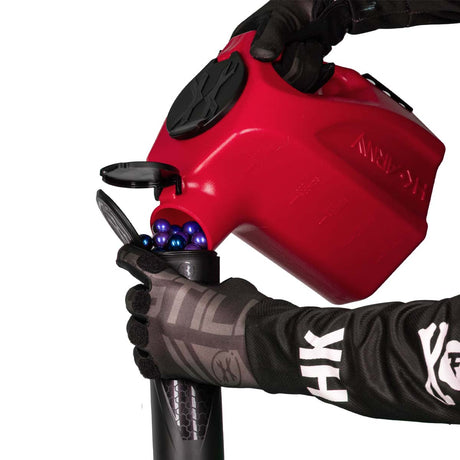 red plastic HK Army Reload Paintball Hauler Caddy loading paintballs into a pod.